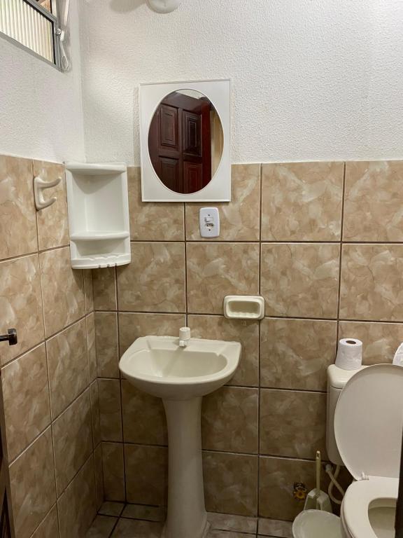 a bathroom with a sink and a toilet and a mirror at Pousada do Suiço in Fortaleza