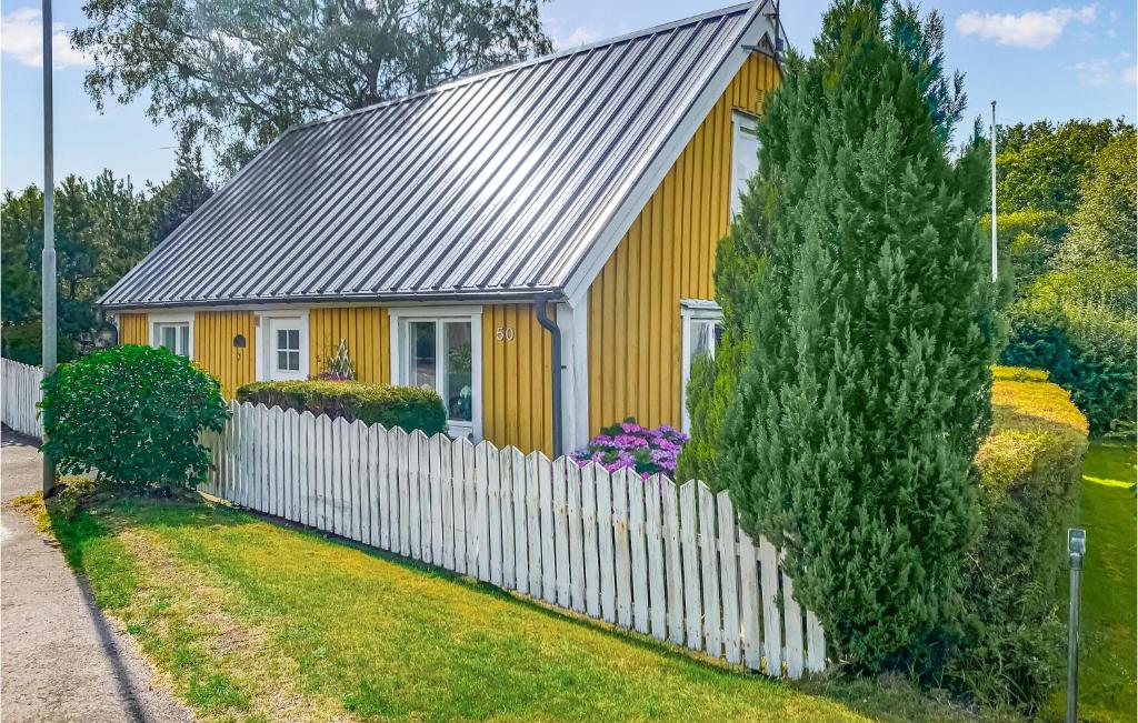 une maison jaune avec une clôture blanche dans l'établissement Amazing Home In Vstra Karup With Wifi, à Västra Karup
