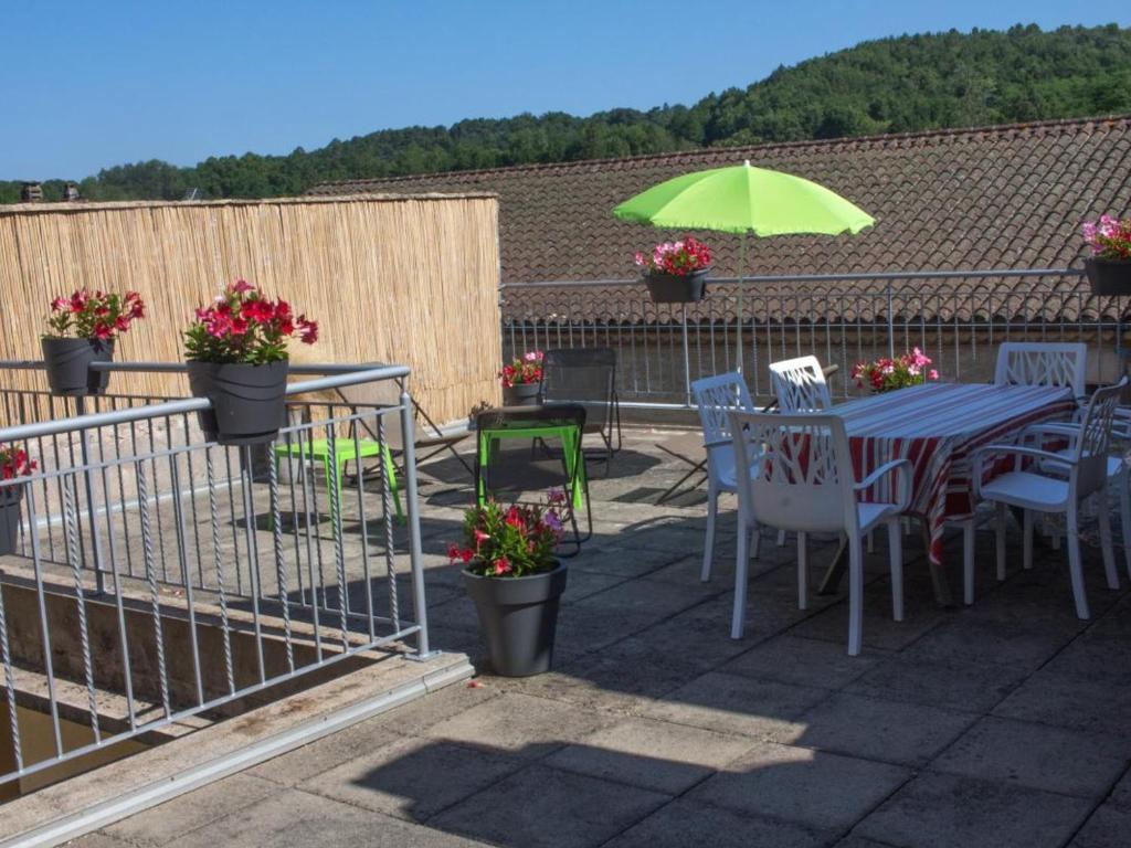 een patio met een tafel en stoelen en een parasol bij Gîte Villefranche-du-Périgord, 4 pièces, 6 personnes - FR-1-616-65 in Villefranche-du-Périgord