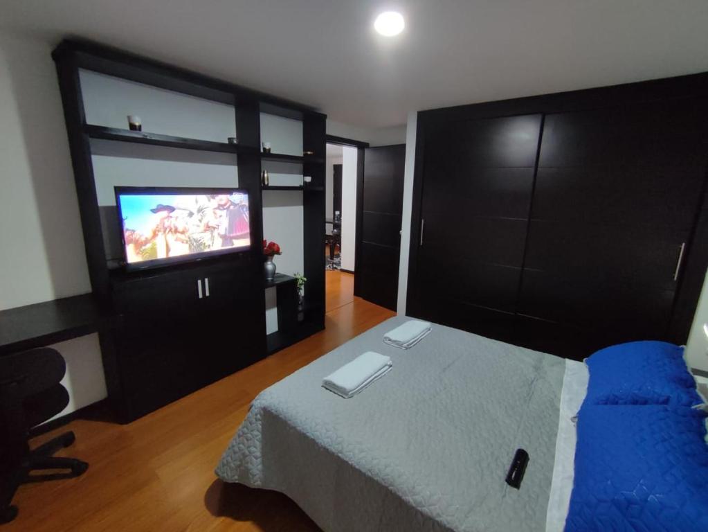 a bedroom with a bed and a flat screen tv at Céntrico luminoso y equipado apto in Pasto