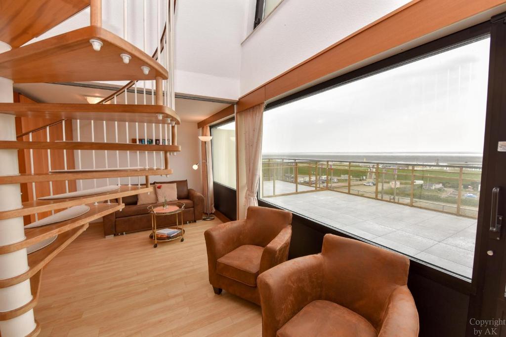 um quarto com cadeiras e uma grande janela com uma varanda em Haus "Jan am Strand" Appartement JAN504 em Döse