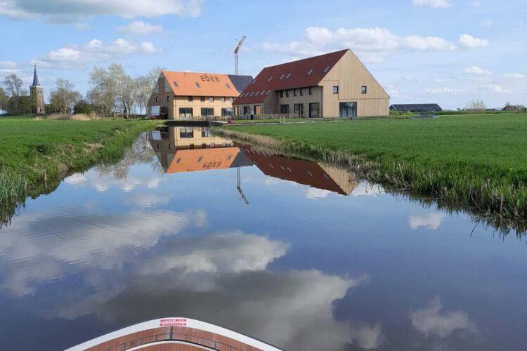 a boat in a river with houses and a windmill at Spacious holiday home in Leons with garden in Leons