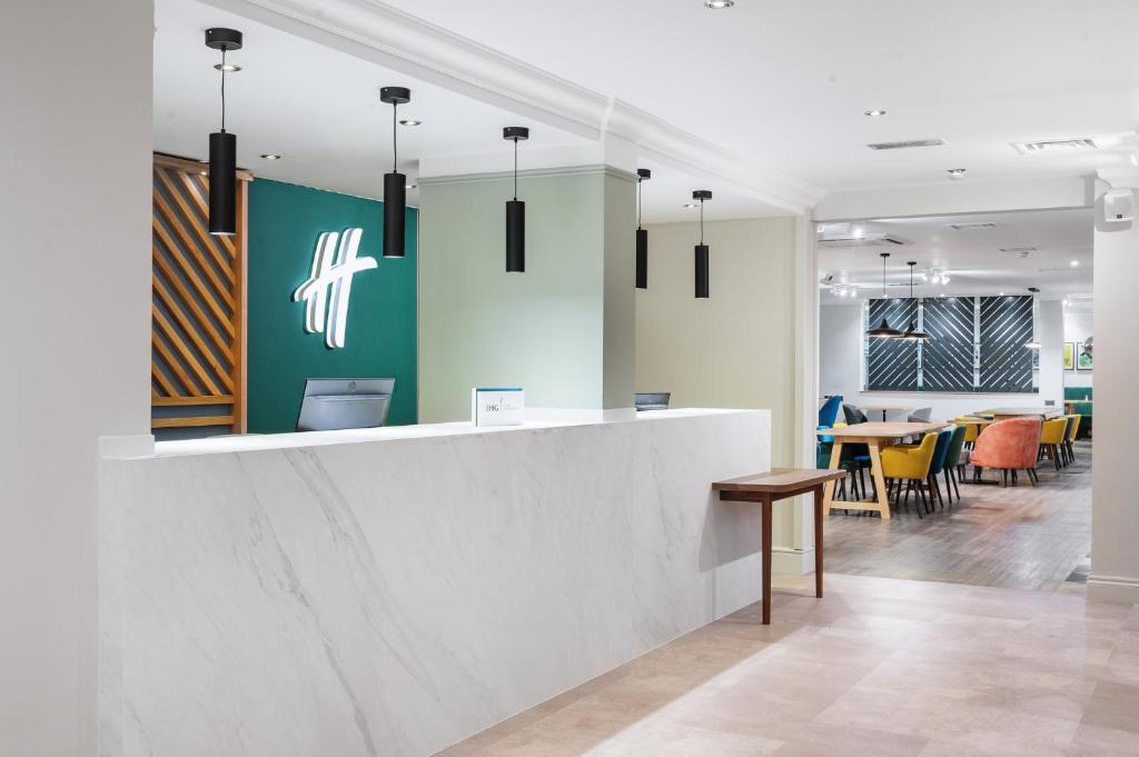 an office with a reception counter and tables and chairs at Holiday Inn Derby/Nottingham by IHG in Derby