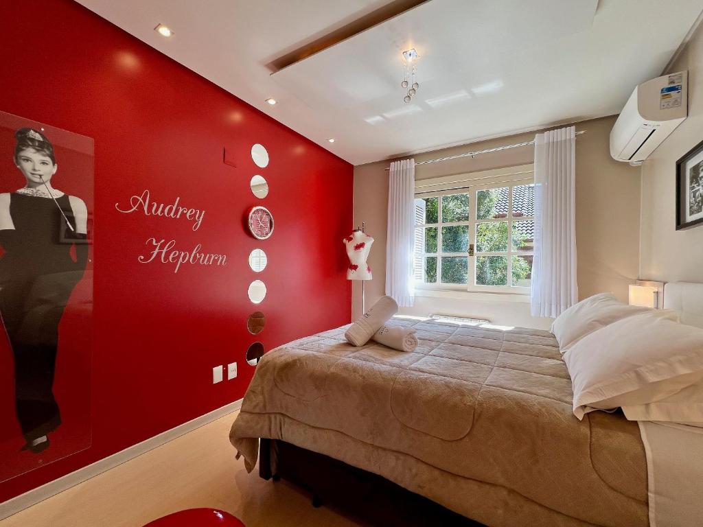 a bedroom with a red wall with a bed at Cobertura Duplex de Cinema 3dorm by Achei Gramado in Gramado