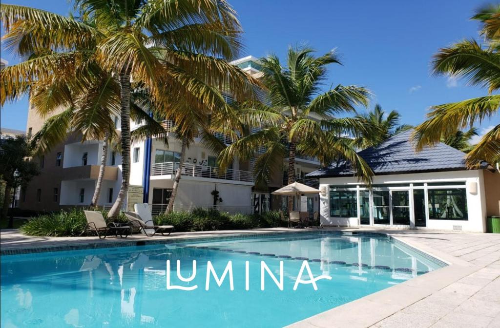 a swimming pool in front of a house with palm trees at Lumina at Jardines Punta Cana Village in Punta Cana