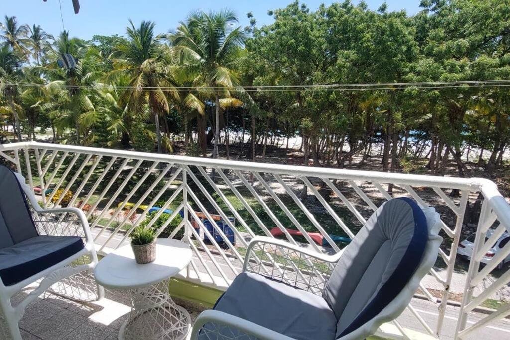 a balcony with chairs and a table and palm trees at Beautiful sea front apartment in Paraíso