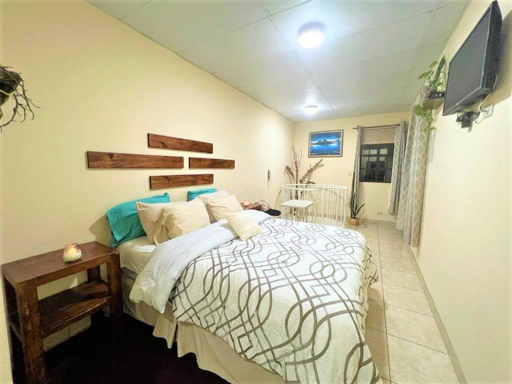 1 dormitorio con 1 cama y TV en la pared en COMFY. Full internet, kitchen, washer and dryer, Netflix, en Chimaltenango