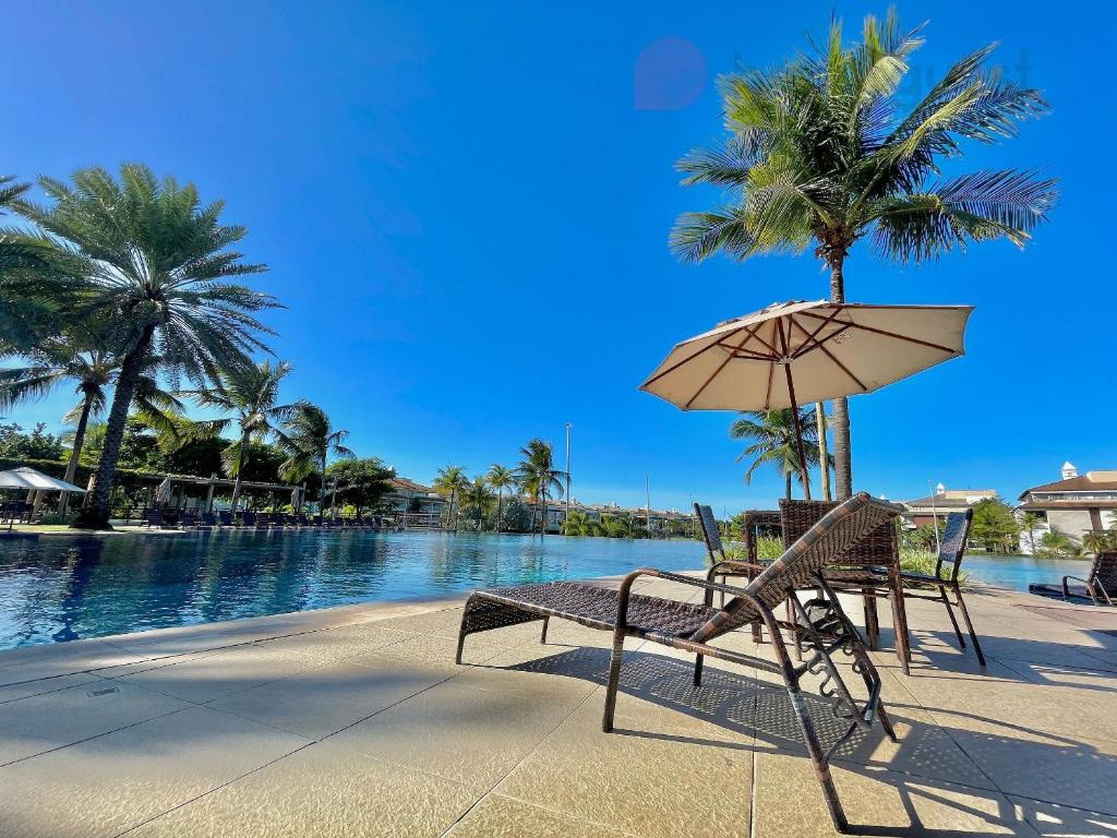 ławka i parasol obok basenu w obiekcie Golf Ville Resort - Porto das Dunas w mieście Aquiraz