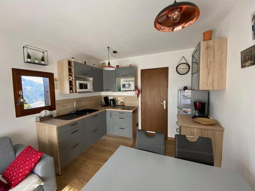 - une cuisine avec des placards gris et une table dans une pièce dans l'établissement Appartement 4 pers, rez-de-jardin, près des pistes, parking, animaux acceptés - FR-1-733-117, à Crest-Voland
