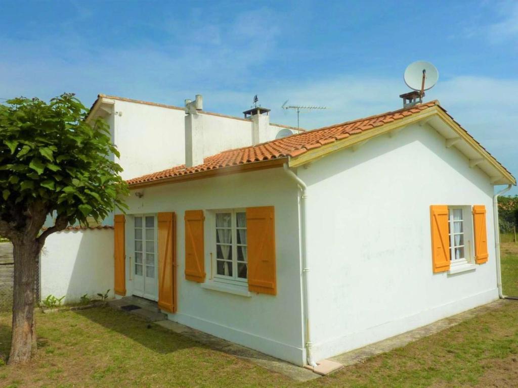 une maison blanche avec des volets orange et un arbre dans l'établissement Maison 4 pièces Saint-Trojan - Terrasse, Parking, 6 Couchages - FR-1-246A-247, à Saint-Trojan-les-Bains