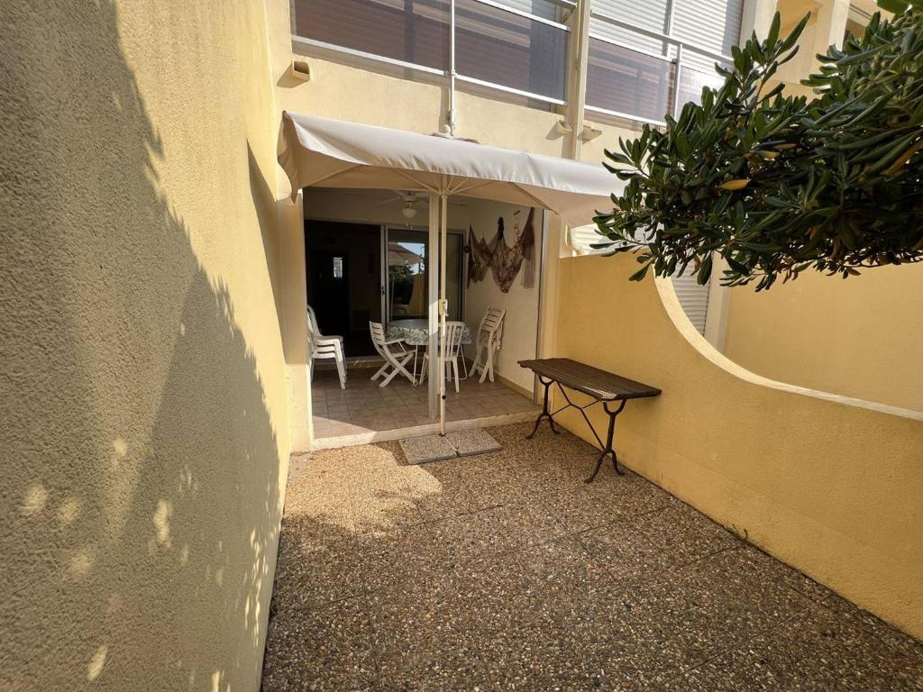 a patio with a table and a white umbrella at Appartement Le Barcarès, 2 pièces, 4 personnes - FR-1-81-589 in Le Barcarès