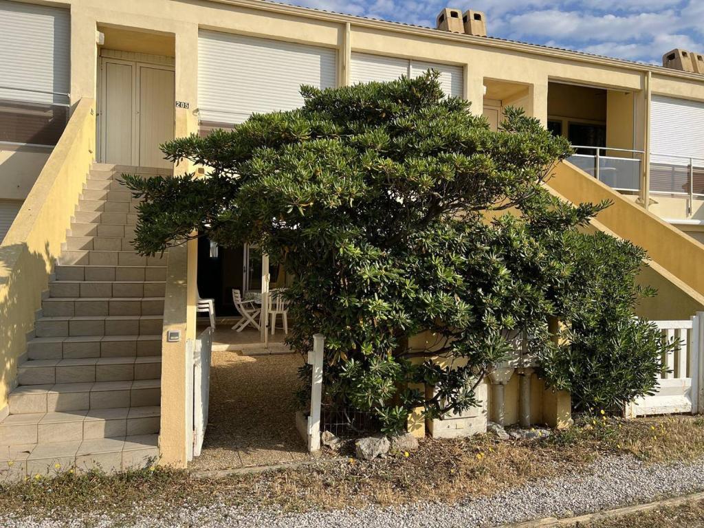 a tree in front of a house with a staircase at Appartement Le Barcarès, 2 pièces, 4 personnes - FR-1-81-589 in Le Barcarès