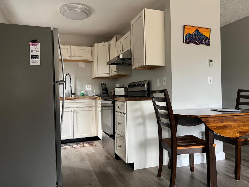 a kitchen with white cabinets and a wooden table and a table and chairs at The Chugach at 1400K in Anchorage