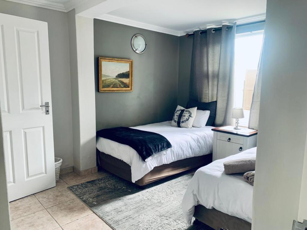 a bedroom with two beds and a clock on the wall at Mulberry Gardens Self Catering in Swakopmund