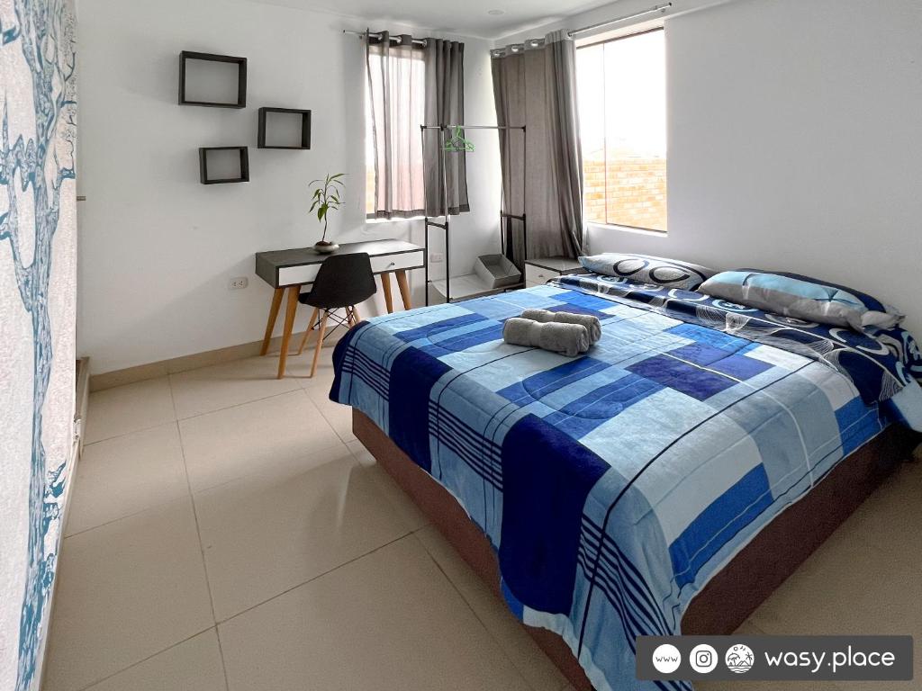 a bedroom with a blue and white bed and a desk at Wasy Rentals in Huanchaco