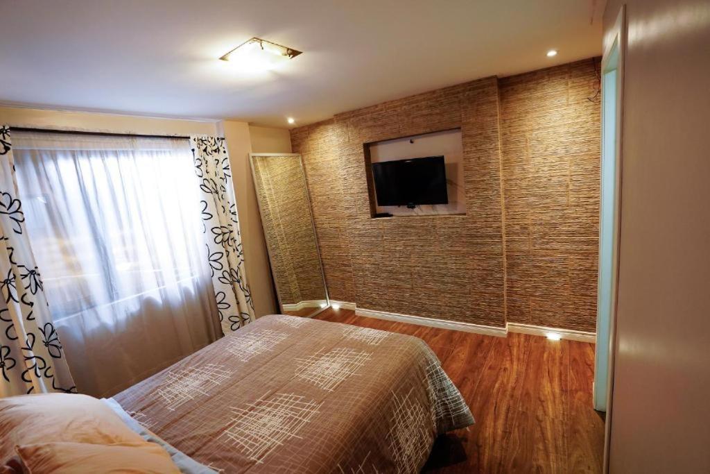 1 dormitorio con 1 cama y pared con TV en Apartamento con jacuzzi y Parqueadero, en Cuenca