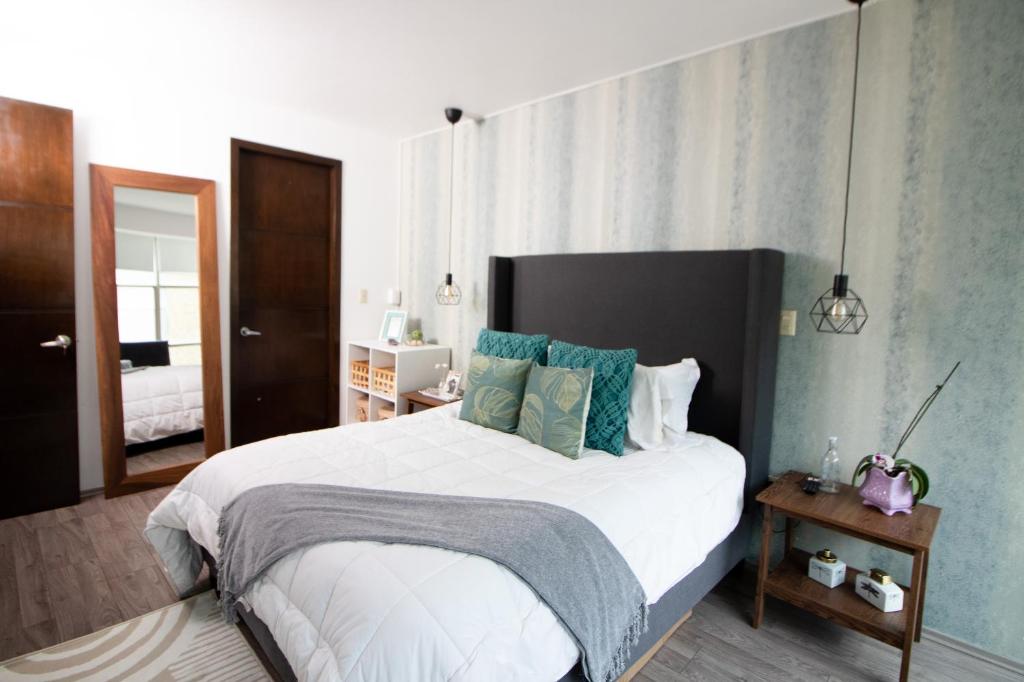 1 dormitorio con 1 cama blanca grande con almohadas azules en D HABITACION MANDALA NEBRASKA 63, en Ciudad de México