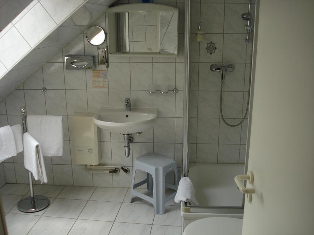 La salle de bains est pourvue d'un lavabo, d'une douche et d'un tabouret. dans l'établissement Hotel Bierstübl, à Sangerhausen