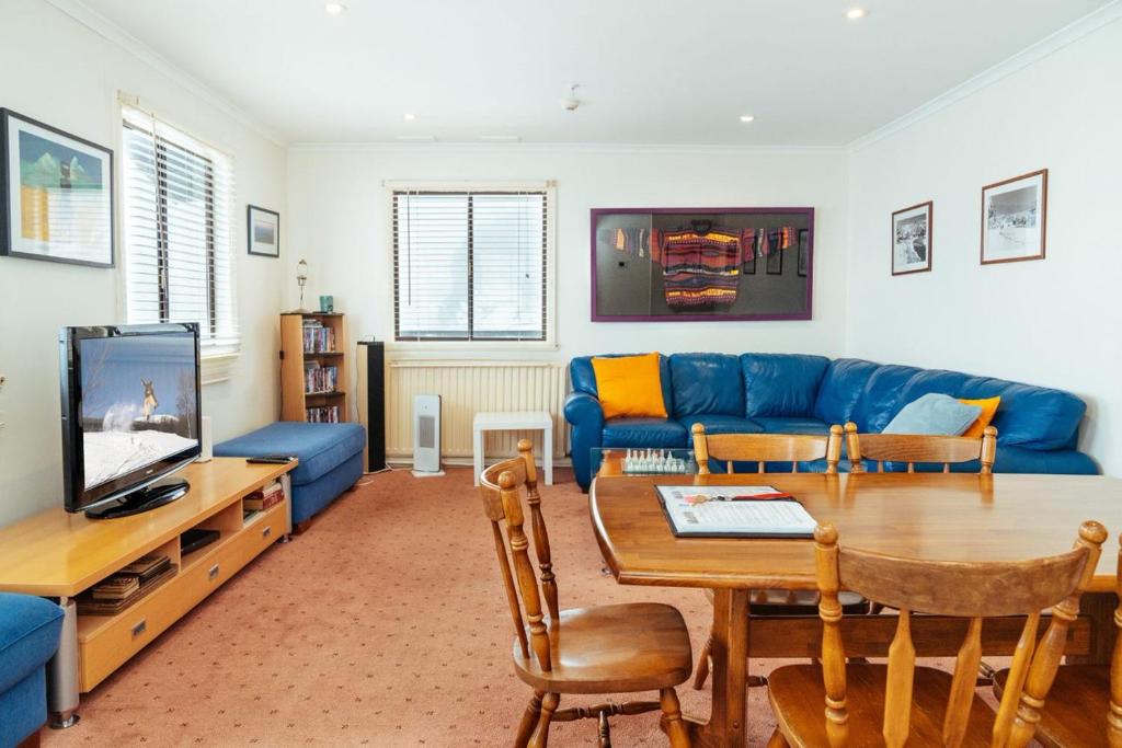 a living room with a blue couch and a table at Enzian 318 in Mount Buller