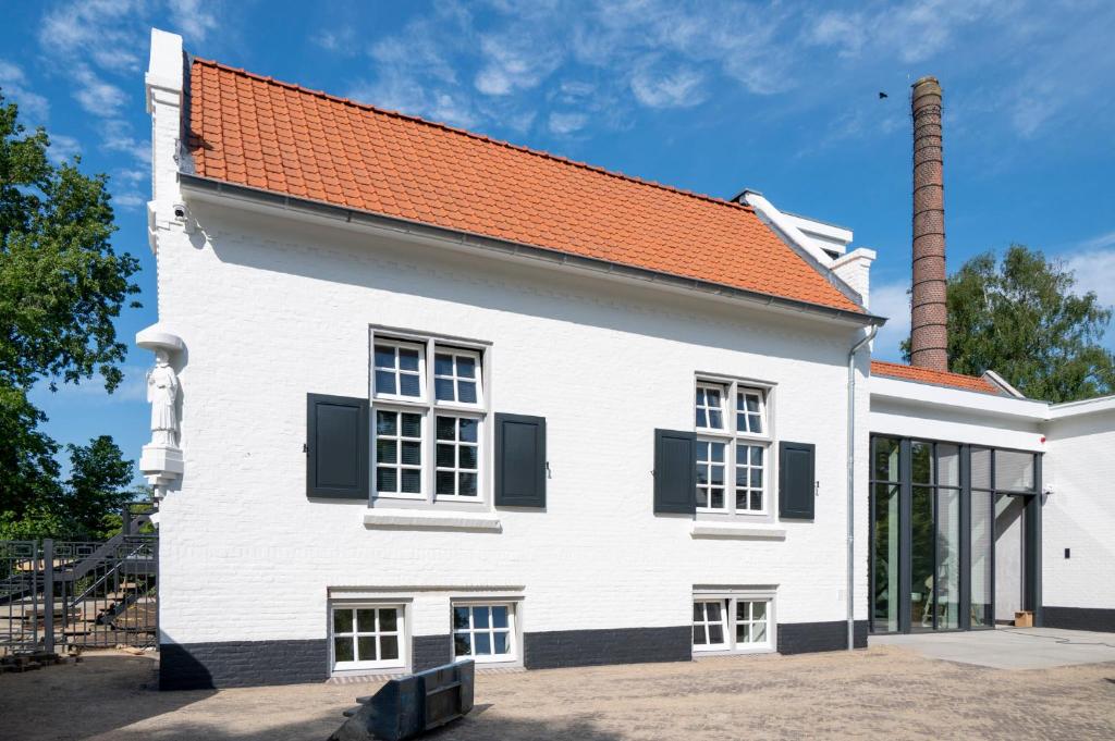ein weißes Gebäude mit rotem Dach in der Unterkunft Lindenhuys Logies in Sint-Oedenrode