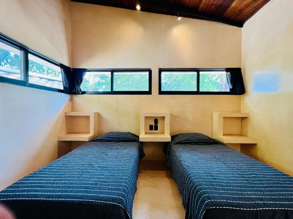 two beds in a small room with windows at 4 Villas equipadas con alberca en Huatulco, Oaxaca in Santa Maria Huatulco