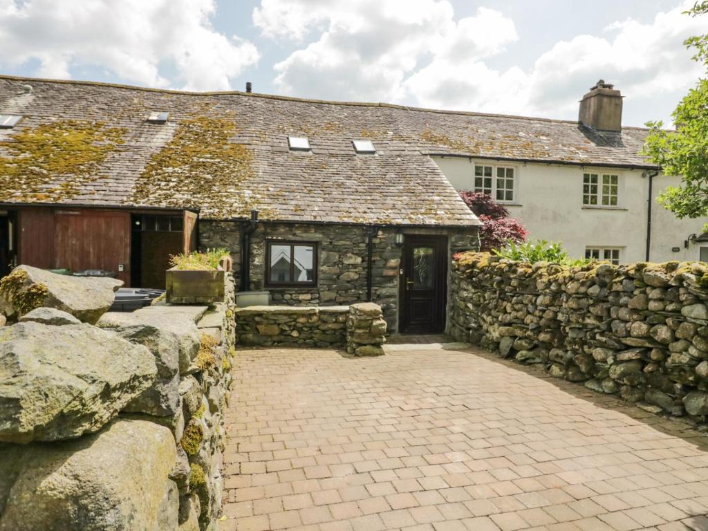 une ancienne maison en pierre avec un mur en pierre et une allée. dans l'établissement Shepherd's Cottage, à Broughton-in-Furness