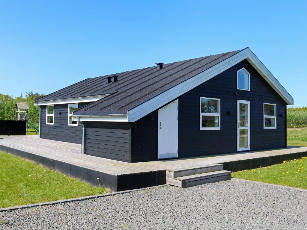 ein schwarzes Haus mit einer Veranda und einer Einfahrt in der Unterkunft 8 person holiday home in Hadsund in Hadsund