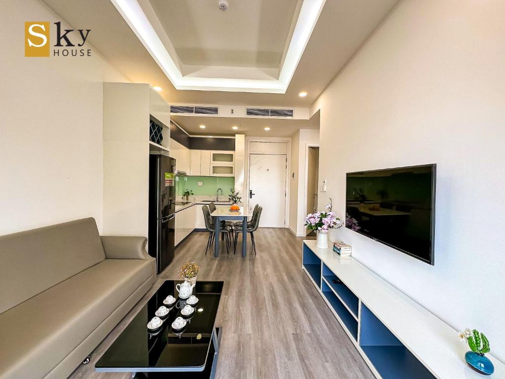 salon z kanapą i telewizorem na ścianie w obiekcie Sky House Apartment w Tam Kỳ