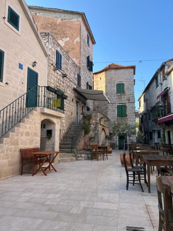 an outdoor patio with wooden tables and chairs and buildings at Residence Bella in Stari Grad