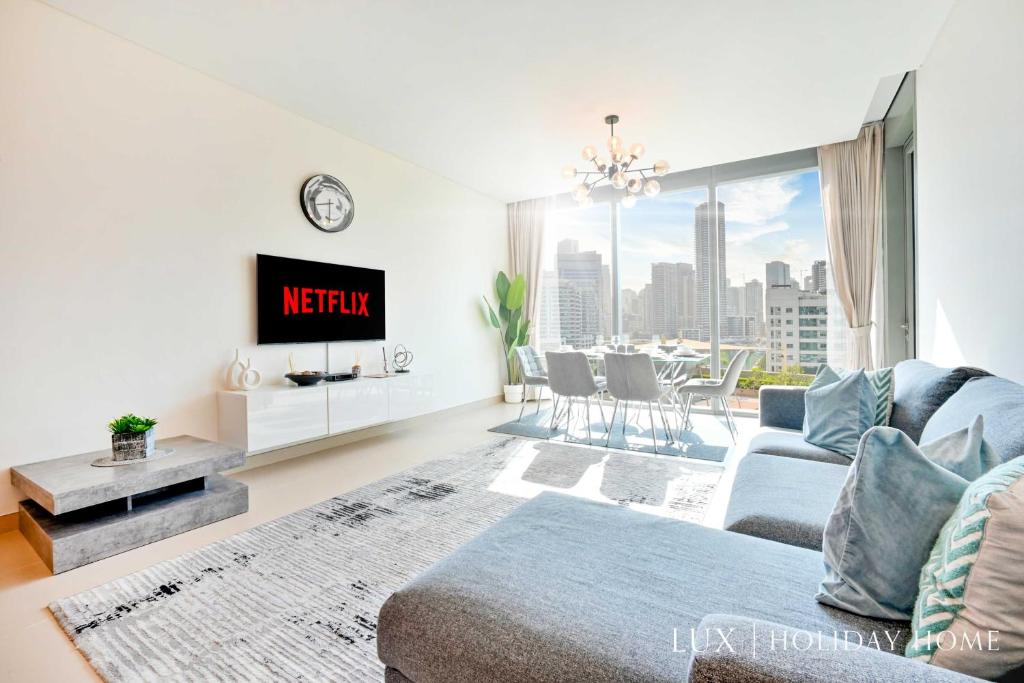 a living room with a couch and a tv at LUX 52 42 Deluxe Marina view suite 1 in Dubai