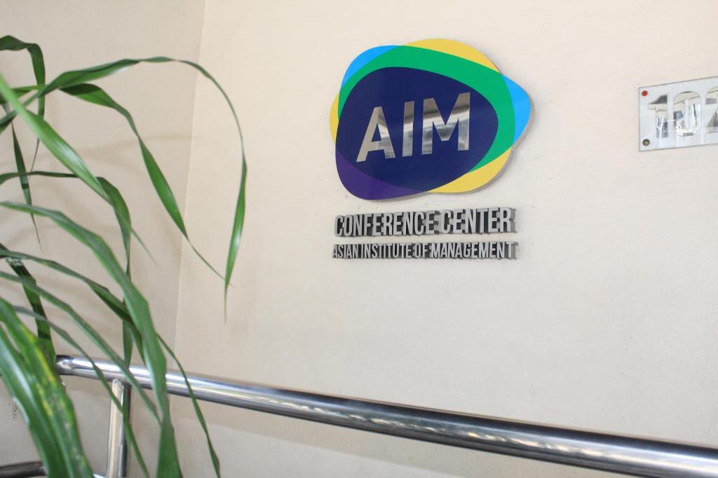 een teken voor anm op een muur naast een plant bij AIM Conference Center in Manilla