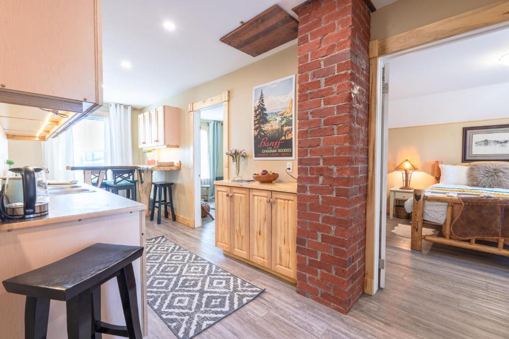 a kitchen and living room with a brick wall at Craftsman's Loft - Heritage charm - AC - 5 min DT in Calgary