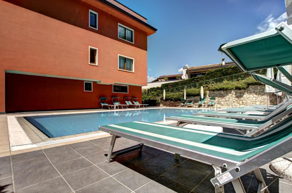 una piscina con tumbonas junto a un edificio en Residence Hotel Vacanze 2000 - Adults Only, en Malcesine