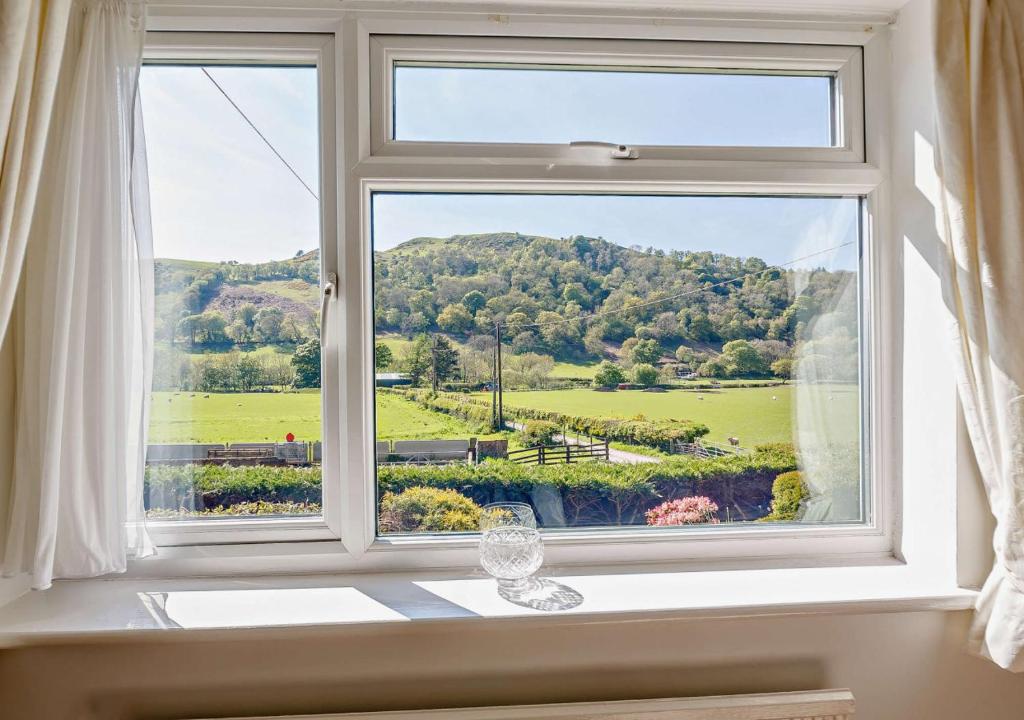 a window with a view of a green field at Llys Pennant in Gwytherin