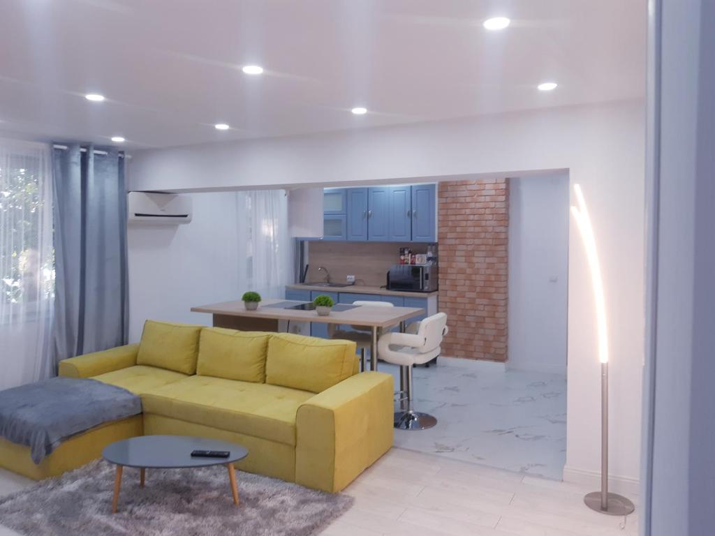 a living room with a yellow couch and a kitchen at Apart Maya in Calafat