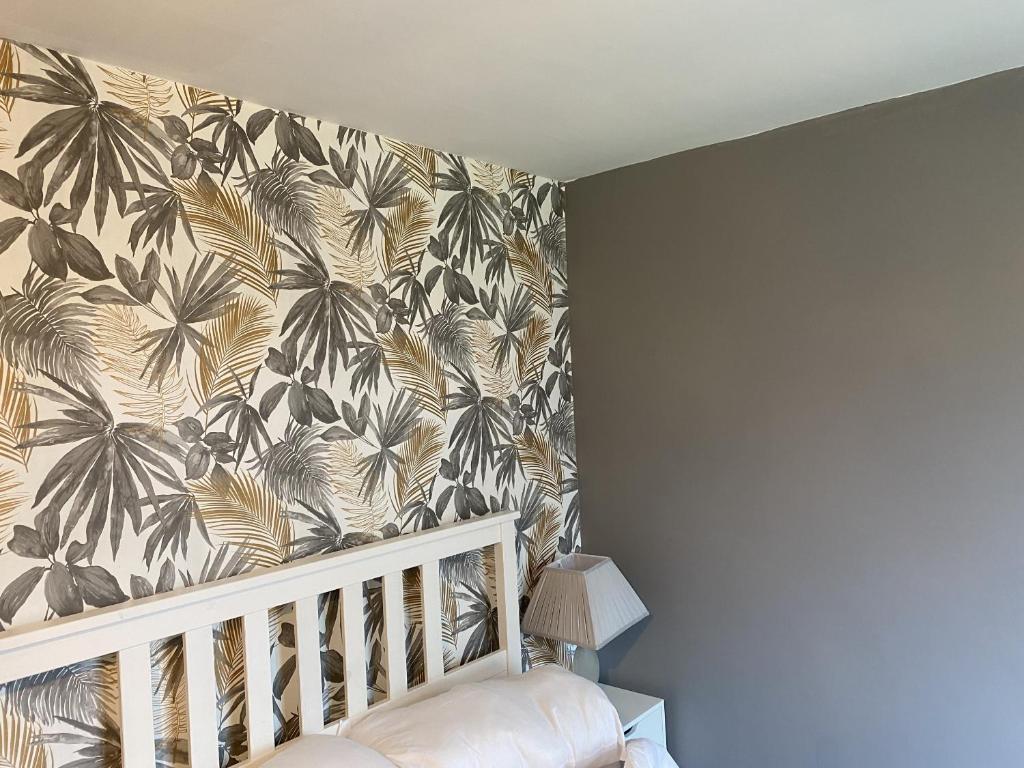 a room with a crib and a wall with a tropical wallpaper at Stansted Airport Guest Rooms in Bishops Stortford