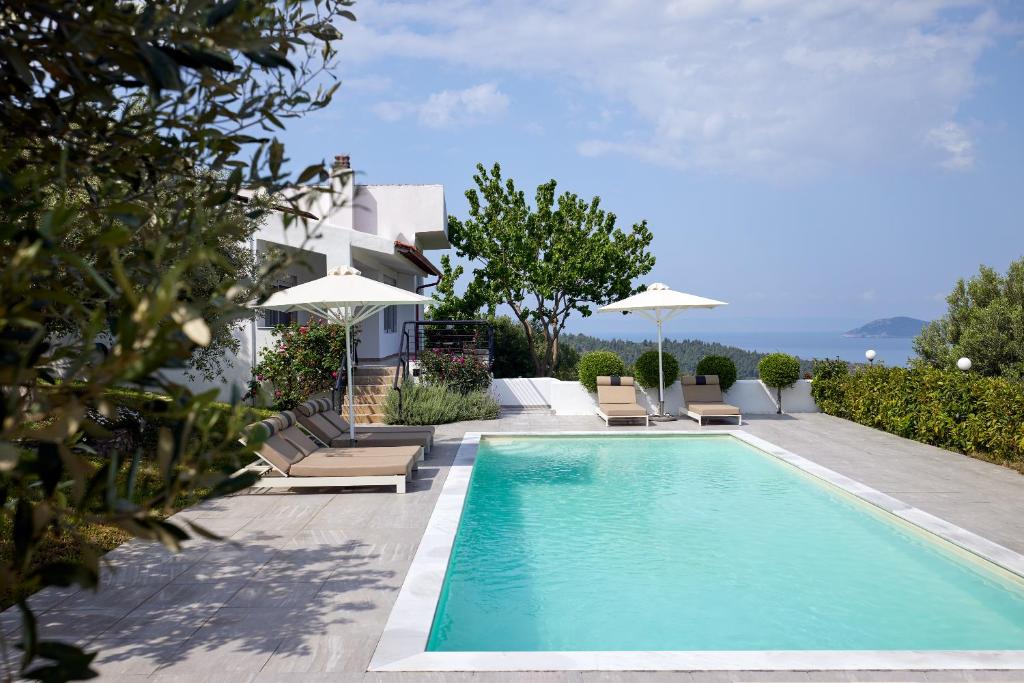 a pool with chairs and umbrellas next to a house at Sithonian Villa in Neos Marmaras