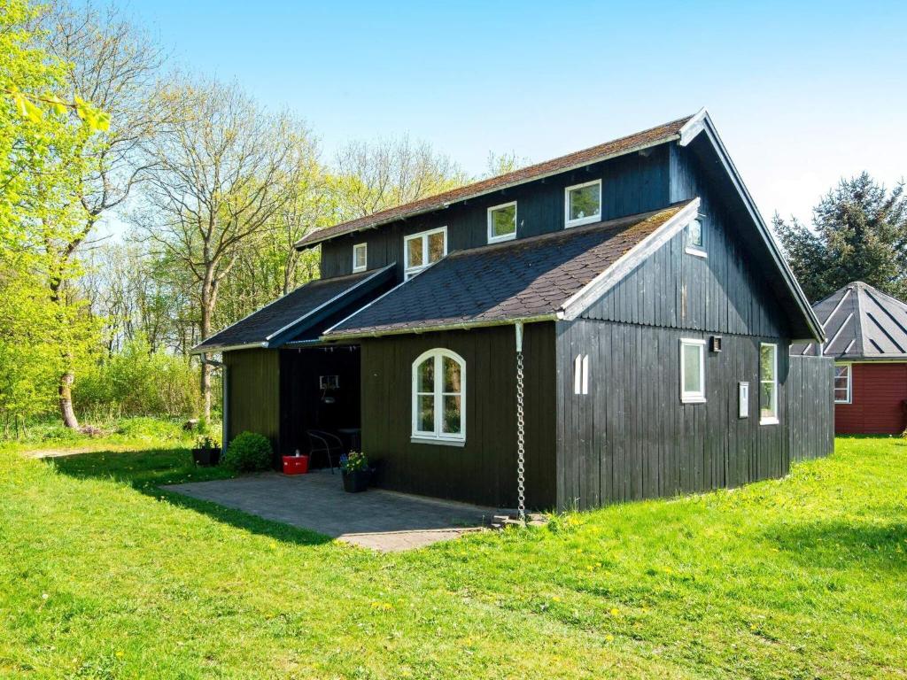 a black barn with a black roof on a green field at Holiday home Hovborg XI in Hovborg