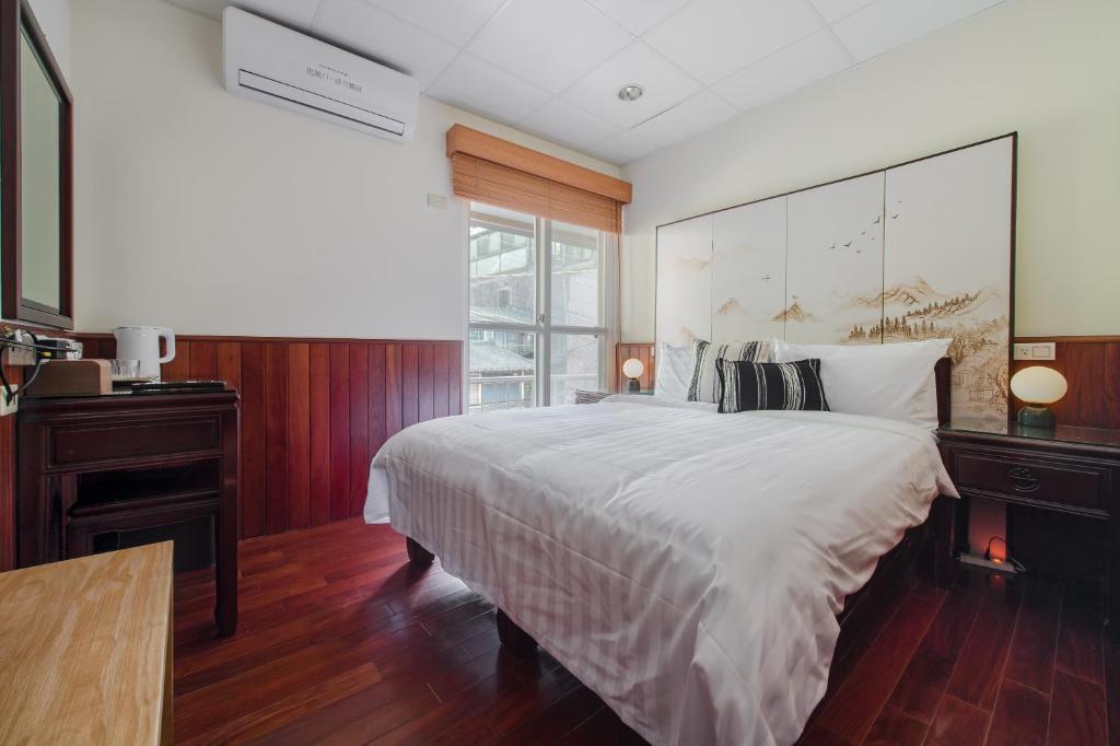 a bedroom with a large white bed and a window at H&amp; Jiufen The Dragon Inn in Jiufen