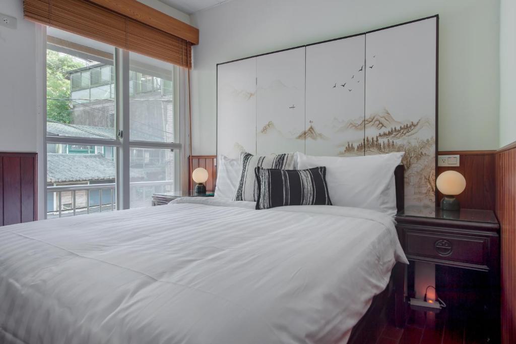 a bedroom with a large white bed and a large window at H&amp; Jiufen The Dragon Inn in Jiufen