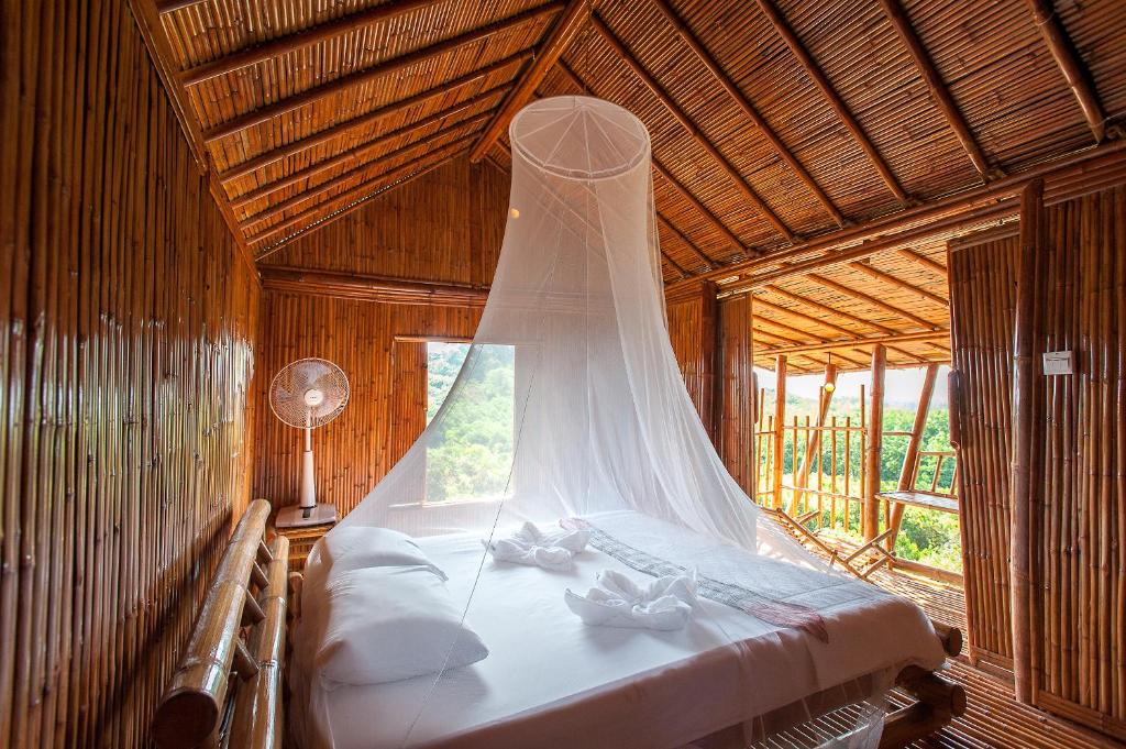 a bed in a wooden room with a veil at Phuree Hut in Ko Phayam