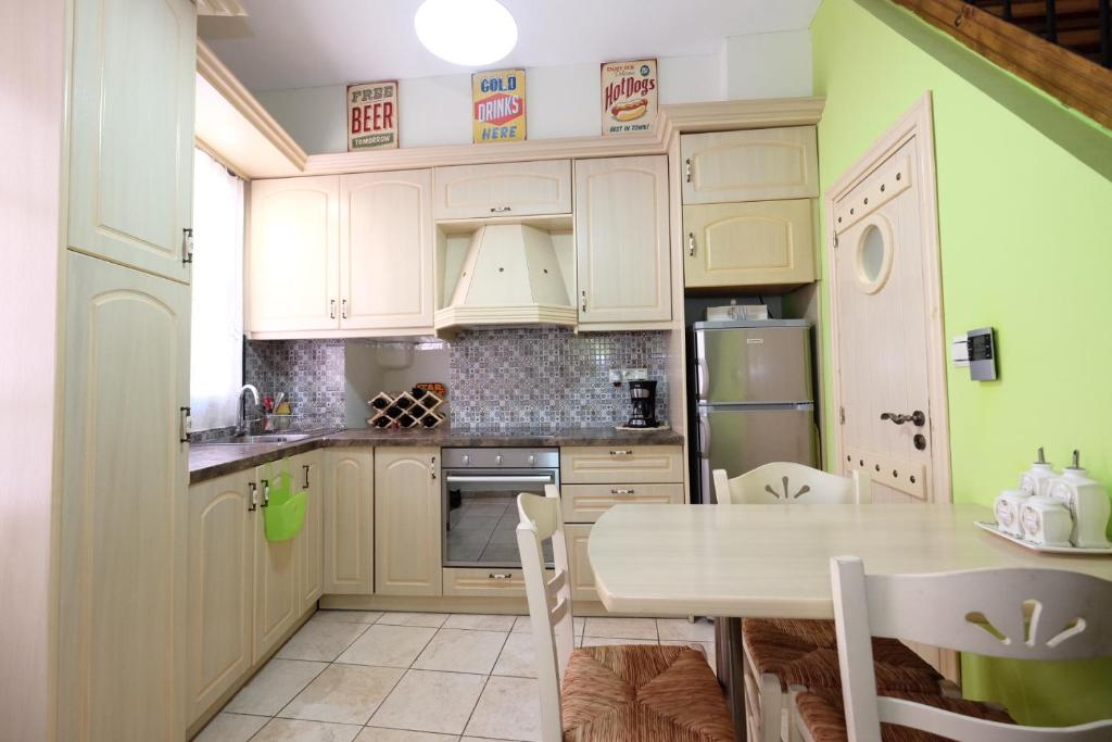 une cuisine avec des placards blancs et une table avec des chaises dans l'établissement Castle Maisonette, à Chios