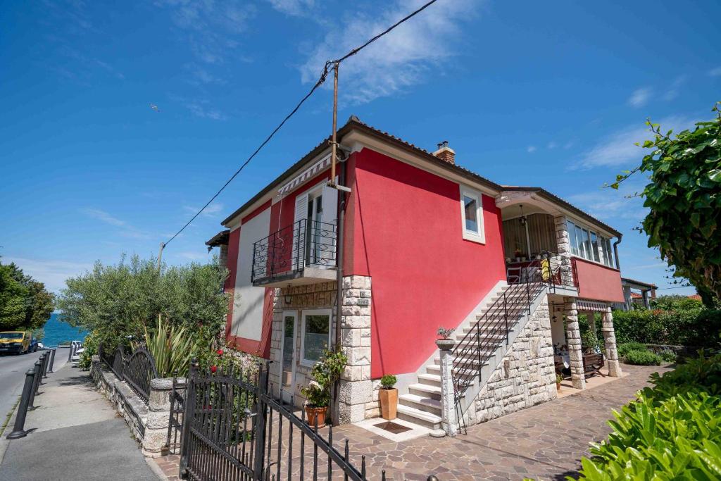 czerwony dom ze schodami przed ulicą w obiekcie Soraja Apartments Izola w mieście Izola