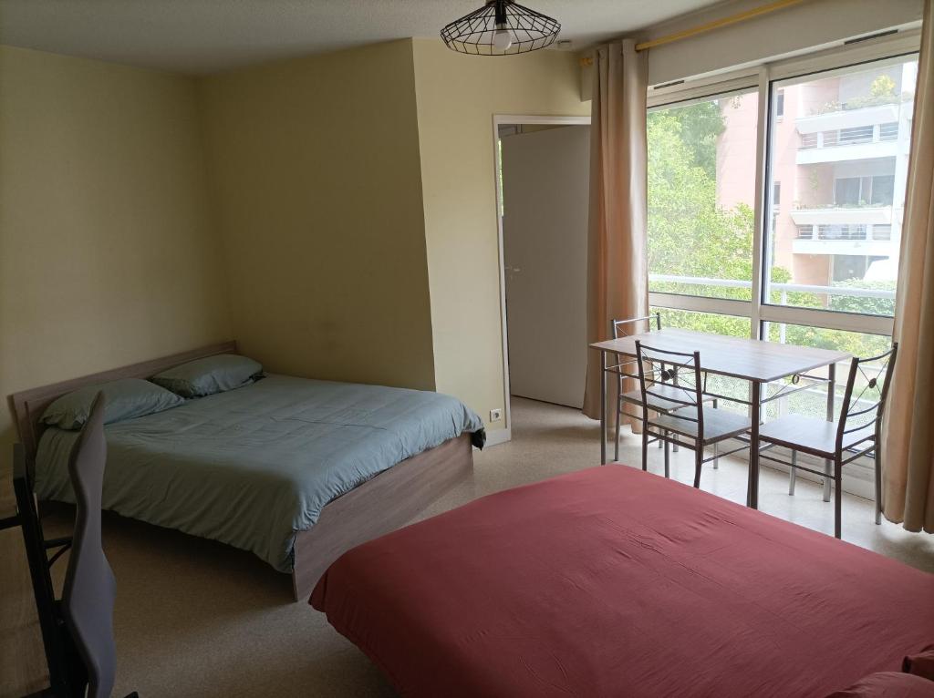 - une chambre avec 2 lits, une table et une fenêtre dans l'établissement T1 confortable situé 100m plage des Minimes, à La Rochelle