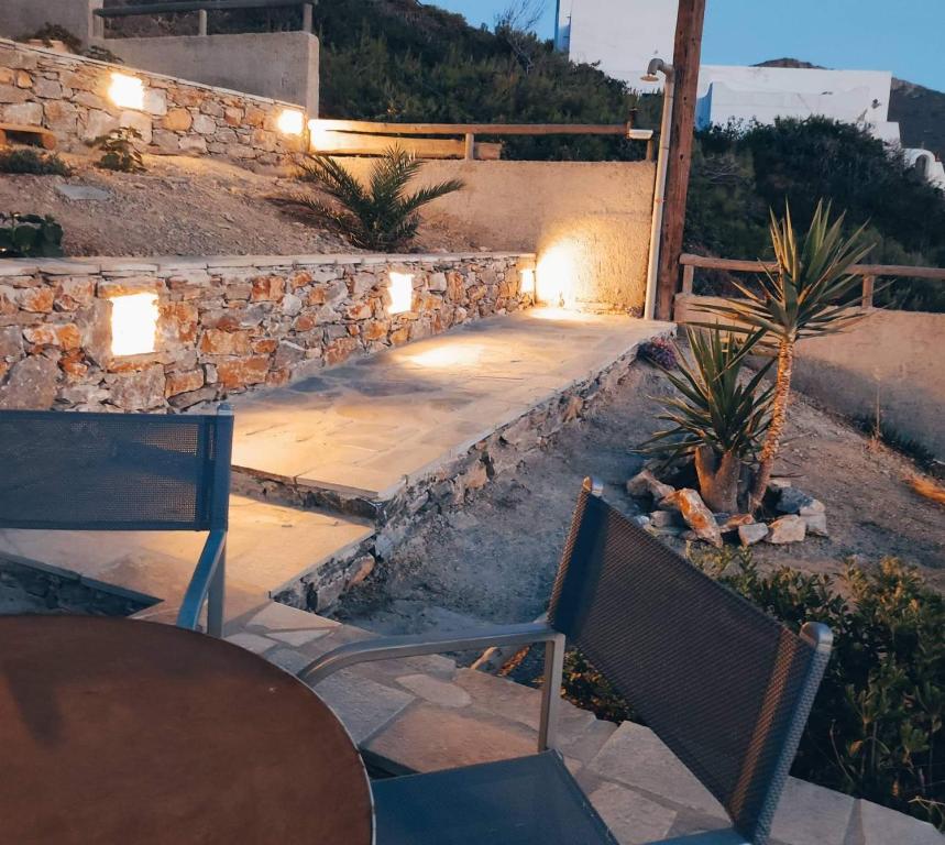 a patio with chairs and a table and a stone wall at Alezina studios in Amorgos