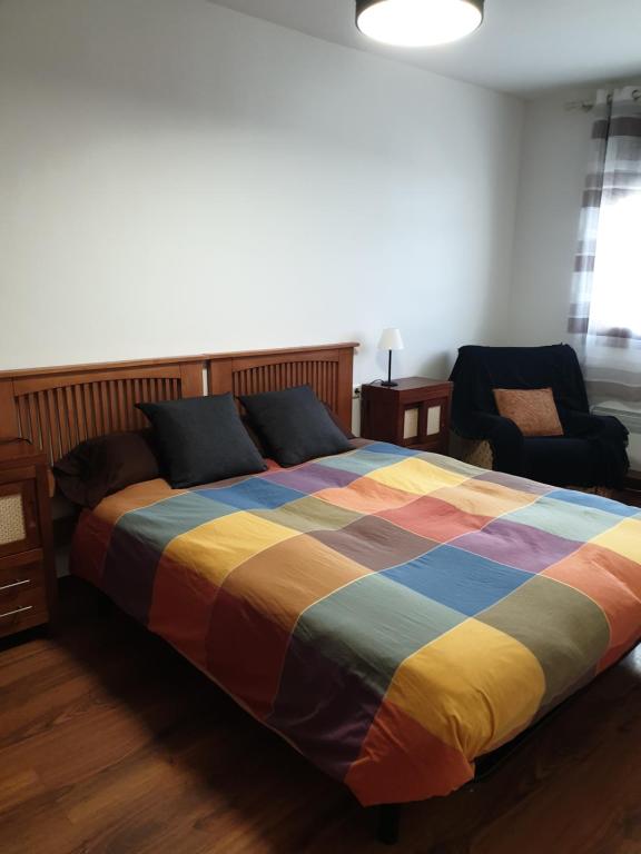 een slaapkamer met een kleurrijk bed en een stoel bij El Pico del Sombrero, tu lugar para desconectar. in Mora de Rubielos