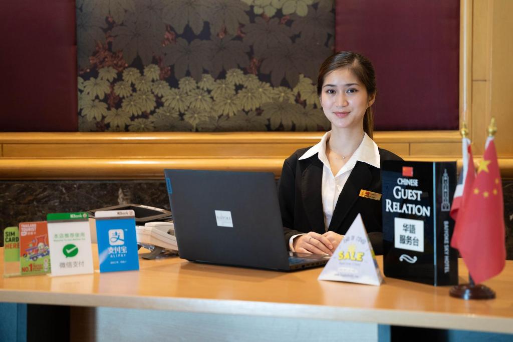 A guest-relations desk offers assistance beside a laptop, sale sign, and national flags.
