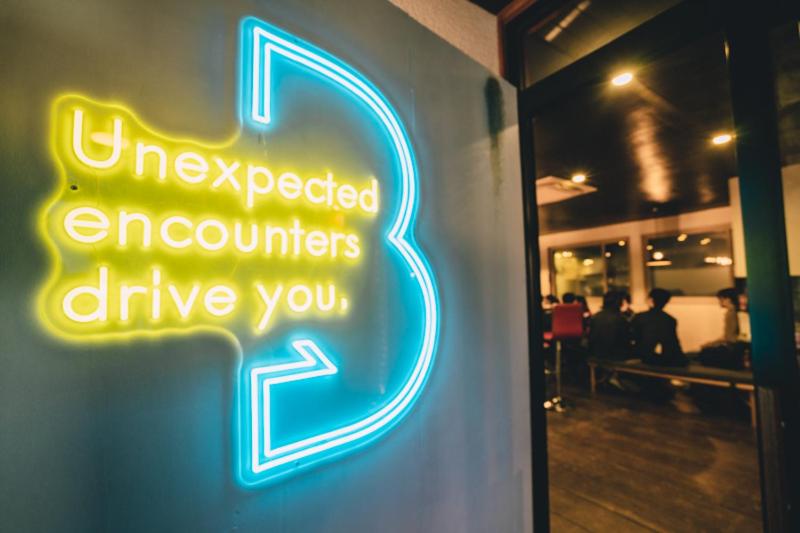 a neon sign that says unexpected encounters drive you at Tug-B Bar & Hostel in Otaru