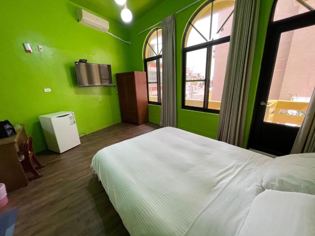 a bedroom with green walls and a white bed at Chunfa B&B in Huxi