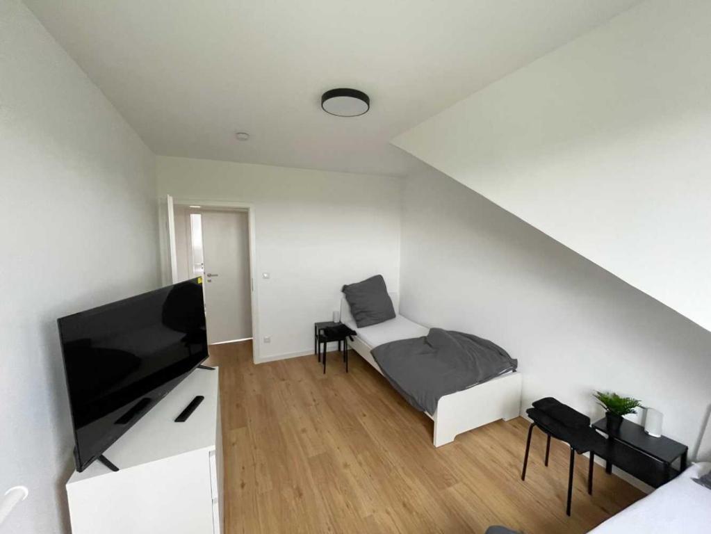 een kleine witte kamer met een bed en een flatscreen-tv bij Apartments in Rosbach vor der Höhe in Rosbach vor der Höhe